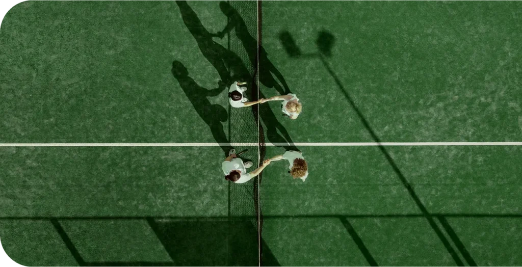 Padel játékosok kezet fognak egy padel pályán